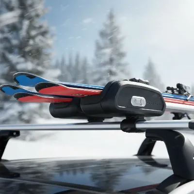 A close-up view of a ski and snowboard carrier securely mounted on an aerodynamic crossbar on a car roof, holding skis.